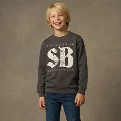 Junge in grauem Sweatshirt und Jeans lächelt vor neutralem Hintergrund. Junge in grauem Sweatshirt und Jeans lächelt vor neutralem Hintergrund.