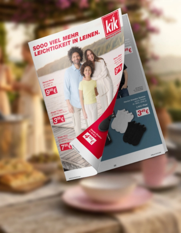 Schwebender KiK‑Katalog mit einem Familienfoto und Kleidungspreisen, im Vordergrund ein unscharfer Outdoor‑Tisch mit Blumen und einer Tasse.