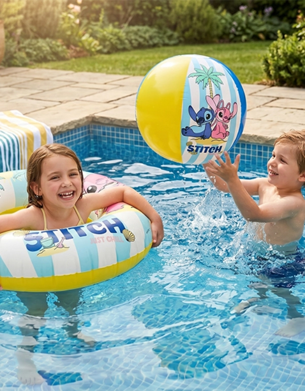 Zwei Kinder spielen an einem sonnigen Tag in einem Gartenpool mit einem Lilo‑&‑Stitch‑Strandball und einem passenden Schwimmring.