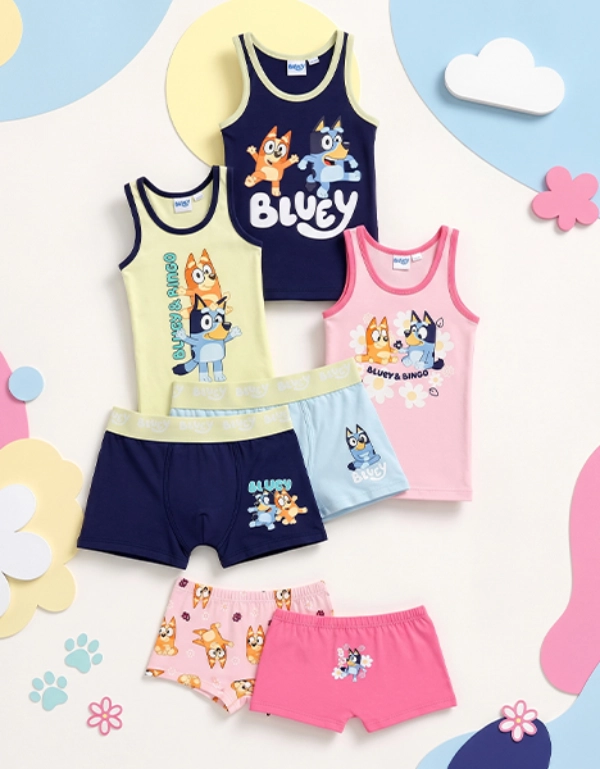 Kinder‑Schlafanzug‑Set mit Bluey‑ und Bingo‑Motiven, bestehend aus Tanktops und Shorts in Pastellfarben vor einem verspielten Hintergrund mit Blumen und Wolken.