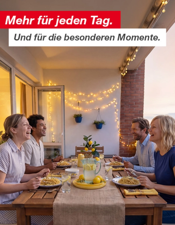 Vier Personen genießen am Abend eine Mahlzeit mit Pasta und Zitronenlimonade auf einem dekorierten Balkon mit Lichterketten und Topfpflanzen.